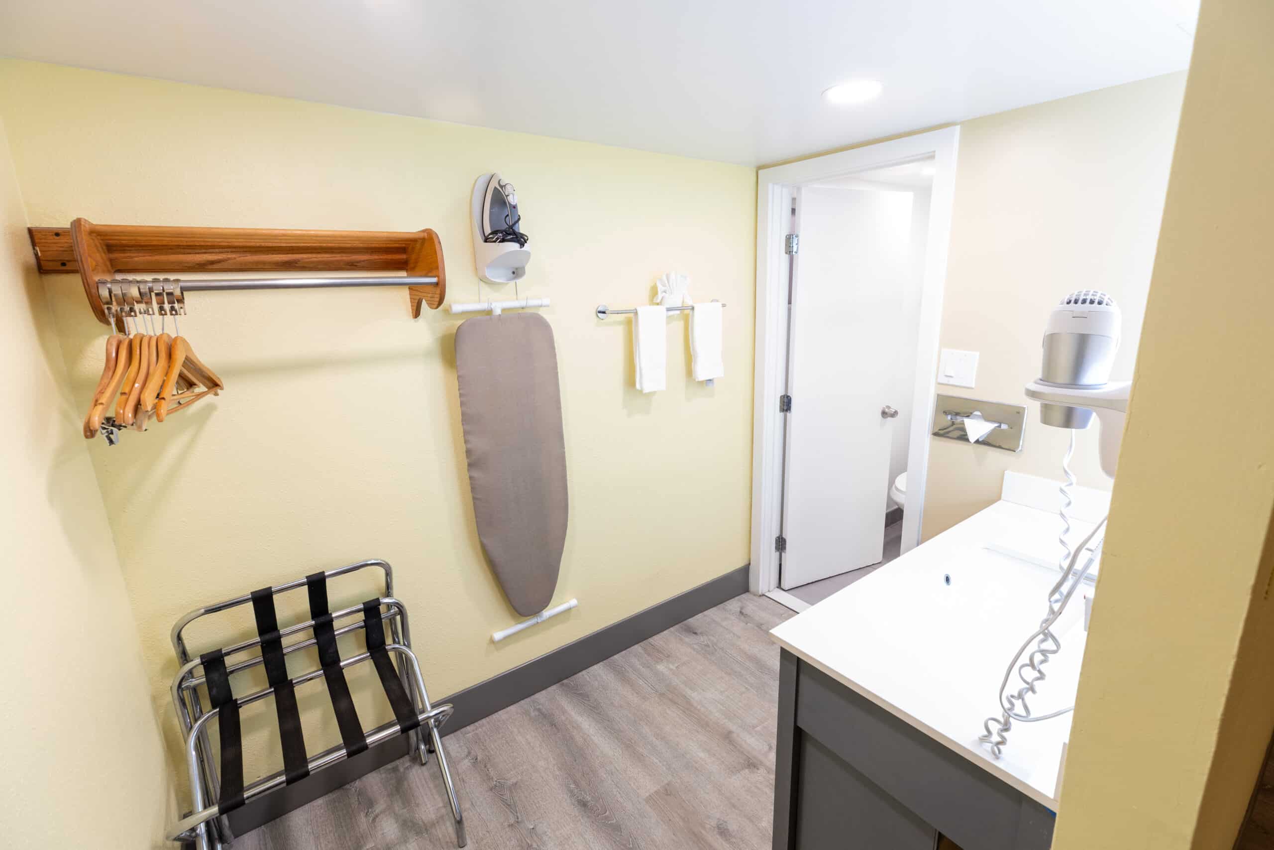 Kings House closet and vanity area with hangers, ironing board, luggage rack, and sink counter
