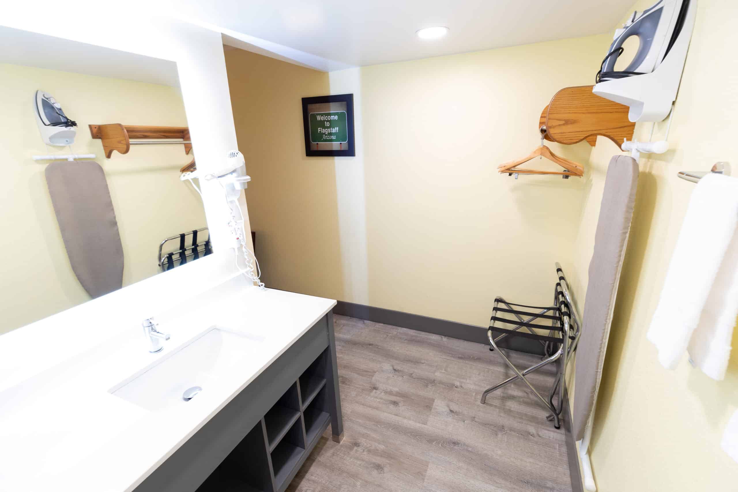 Kings House vanity counter with sink and mirror beside closet area with hangers and luggage rack