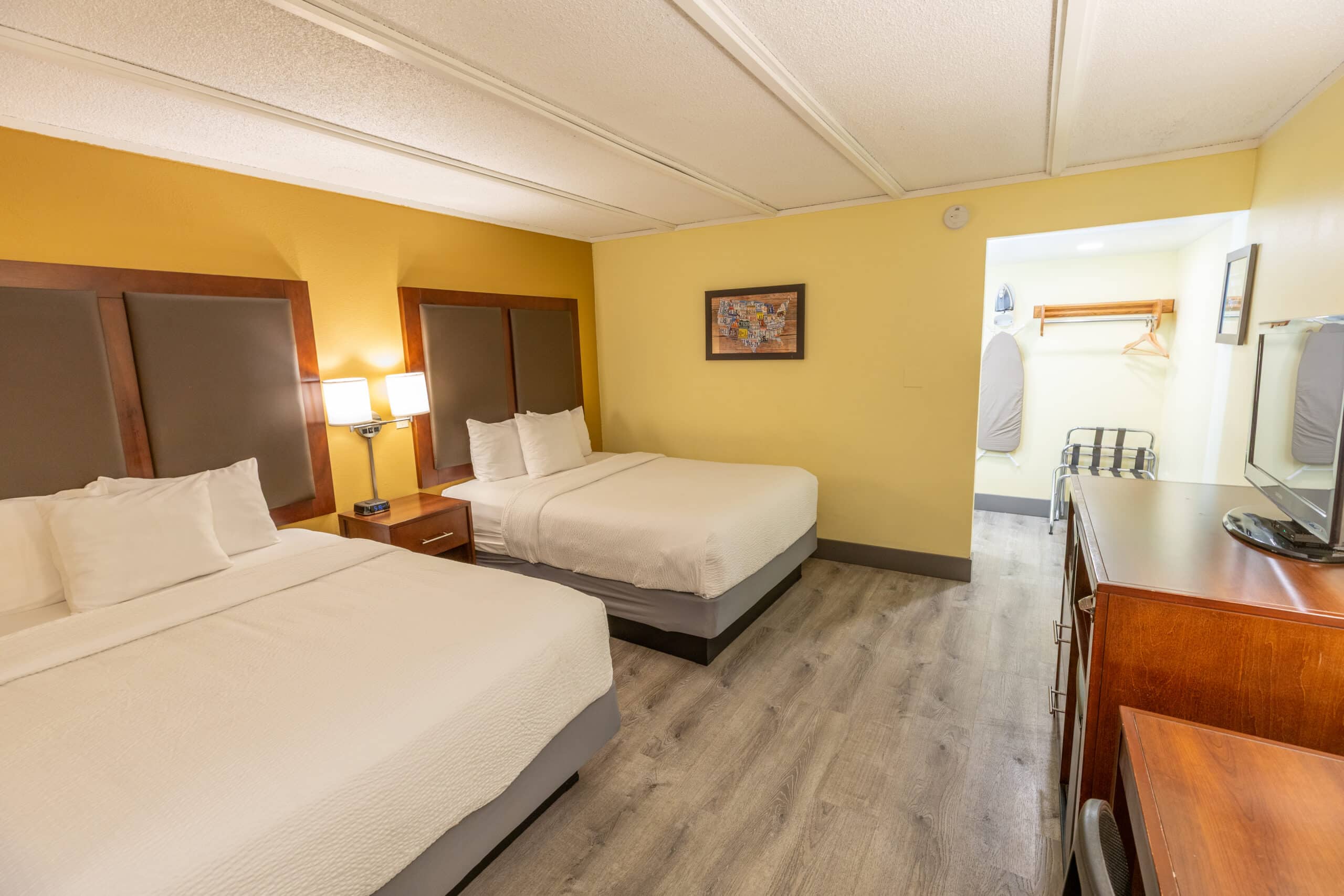 Kings House two-queen room with TV console, open closet area, and view of both beds