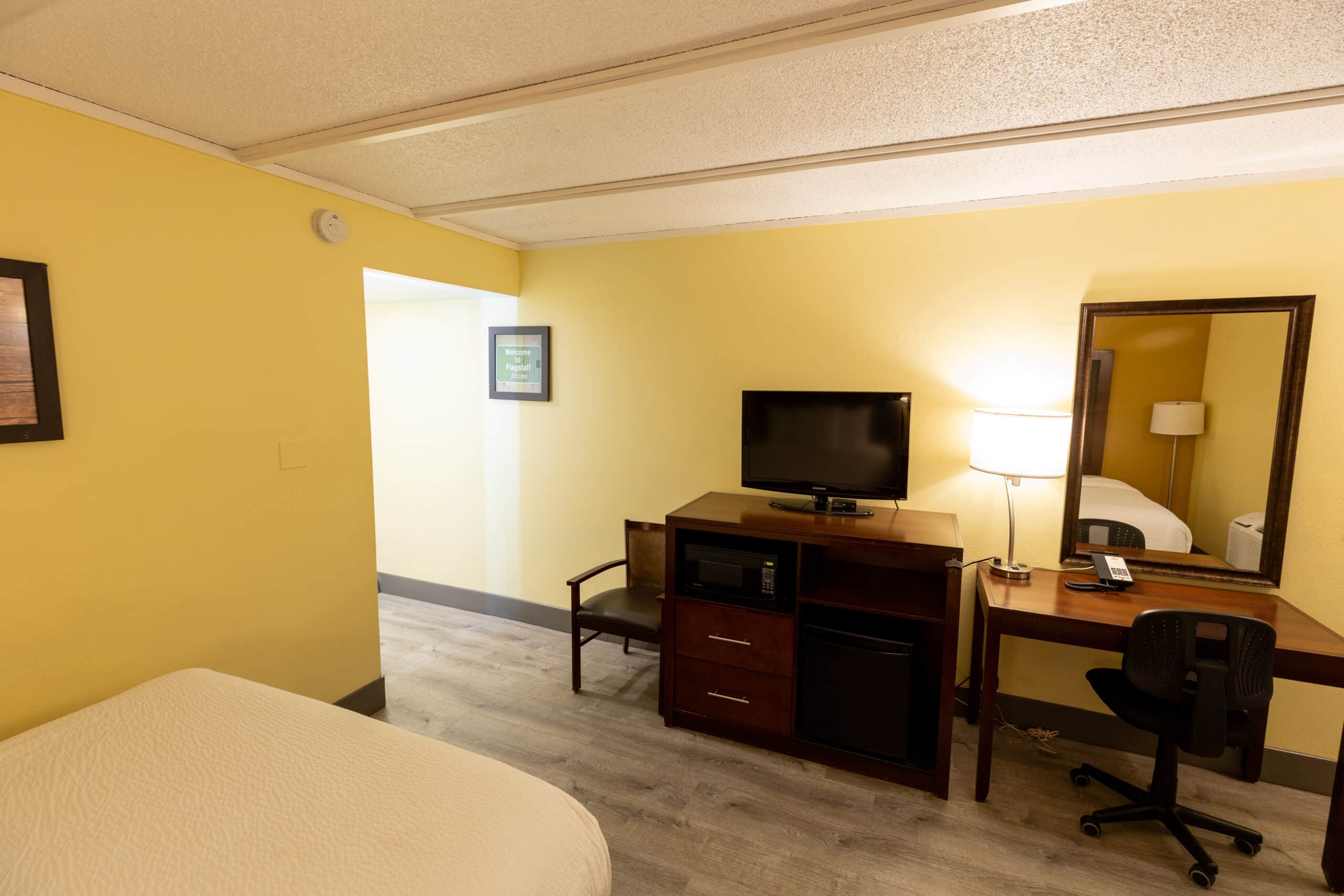 TV console with microwave and mini fridge beside desk, lamp, and large mirror in Kings House guest room